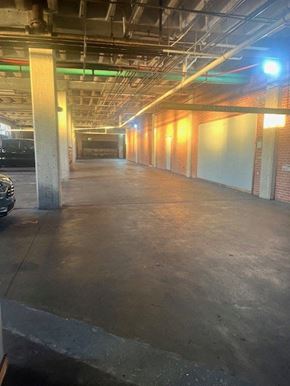 Oklahoma City apartment for rent - A long, empty parking garage with concrete floors and brick walls.