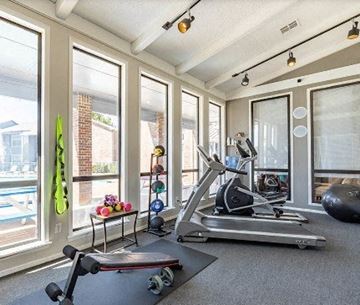 Lawton apartment for rent - A home gym with a treadmill, weights, and exercise balls.