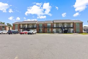 Memphis apartment for rent - A parking lot in front of a multi-story brick building.