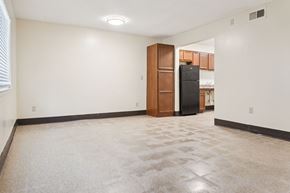 Memphis apartment for rent - A spacious room with a carpeted floor and a black refrigerator in the corner.