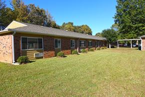 Parsons apartment for rent - a view of the exterior of a brick building with a large grassy area in front of