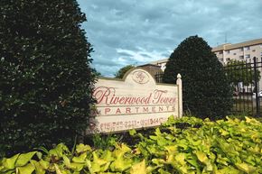 Madison apartment for rent - a sign in front of a building with trees and bushes