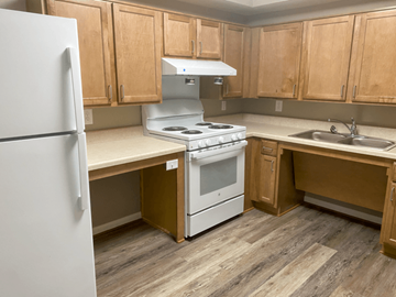 Franklin apartment for rent - A kitchen with a white fridge, white stove, and wooden cabinets.