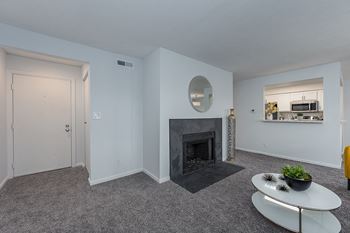 A living room with a fireplace and a kitchen in the background