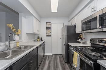 A kitchen with white cabinetry and black appliances
