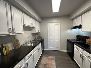 Toledo townhouse for rent - a kitchen with white cabinets and black counter tops