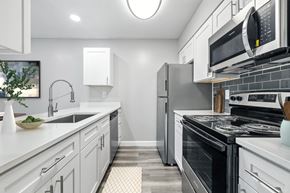Indianapolis apartment for rent - A modern kitchen with white cabinets and stainless steel appliances.at Hanna Village, Indianapolis, IN