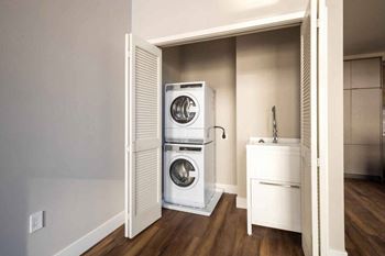 A white washing machine and dryer are stacked in a small laundry room.