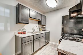 Cincinnati apartment for rent - A kitchen with a black stove top oven and a white sink. at The Apex, Cincinnati, 45239