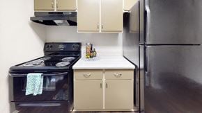 Indianapolis apartment for rent - Compact kitchen with black appliances and range hood at Summit at Keystone Apartments, Indiana, 46220