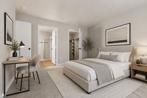Findlay apartment for rent - A bedroom with a large bed, a desk with a chair, and a nightstand with a lamp.