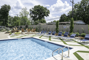 Cincinnati apartment for rent - a swimming pool with chaise lounge chairs and a grassy area with trees in the background at Olde Towne in Kenwood, Ohio, 45243