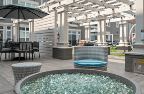 Liberty Township apartment for rent - a patio with a jacuzzi and tables with chairs and umbrellas
