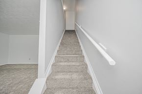 Cincinnati apartment for rent - A staircase with a carpeted runner and white handrails.