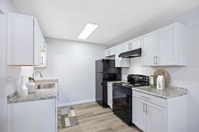 Hamilton apartment for rent - A kitchen with white cabinets and a black refrigerator.