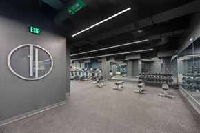 Cincinnati apartment for rent - A gym with a green exit sign and a clock on the wall at Sky Central Apartments, Cincinnati