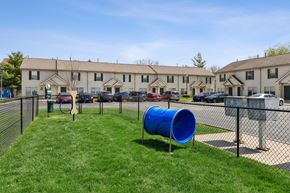 Findlay apartment for rent - A blue barrel is in the grass in front of a chain link fence.