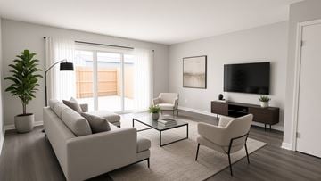 Oregon townhouse for rent - A modern living room with a grey sofa, a white armchair, a glass coffee table, and a television on the wall.