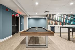 Dayton apartment for rent - A pool table is in the middle of a room with a blue wall and a bookshelf in the background.