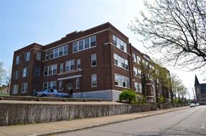 Dayton apartment for rent - A large red brick building with a blue truck parked in front.
