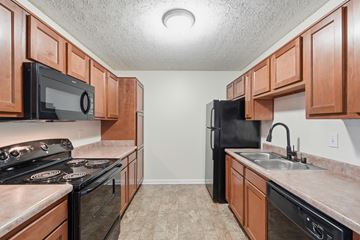 Louisville apartment for rent - A kitchen with black appliances and brown cabinets.