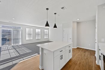 An open kitchen and living room with white cabinets and a white island