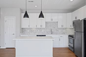 A white kitchen with stainless steel appliances and white cabinets