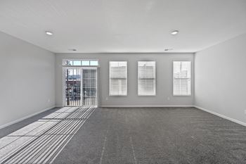 An empty living room with a door to a balcony
