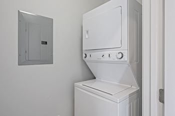 A white washer and dryer in a white laundry room with a white door