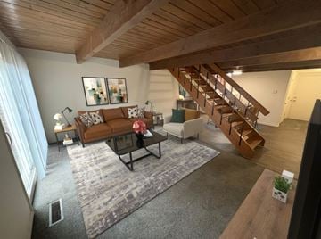 Dayton townhouse for rent - A living room with a brown couch and a wooden staircase.