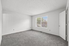 Cincinnati apartment for rent - A room with a carpeted floor and a window showing a view of trees and a fence outside.
