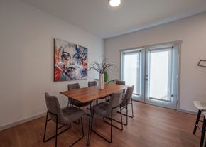 Springdale townhouse for rent - a dining room with a wooden table and chairs and a painting on the wall at The Row on Merchant Apartments, Springdale, Ohio