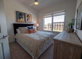 Springdale townhouse for rent - a bedroom with a bed and a large window at The Row on Merchant Apartments, Springdale, OH, 45246
