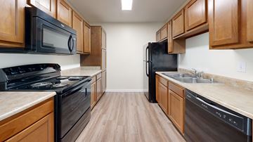 Louisville apartment for rent - A kitchen with wooden cabinets and black appliances.