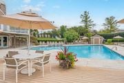Beavercreek apartment for rent - A poolside table with chairs and an umbrella overlooking a pool.