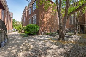 Bellevue apartment for rent - A courtyard with a bench and a tree in front of a brick building.