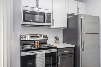 A modern kitchen with a stainless steel refrigerator, microwave, oven, and stove.