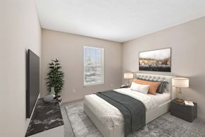 Columbus apartment for rent - A bedroom with a large bed, a flat screen TV, and a potted plant.