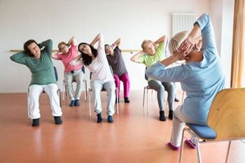 A group of women sitting in a chair doing a yoga pose