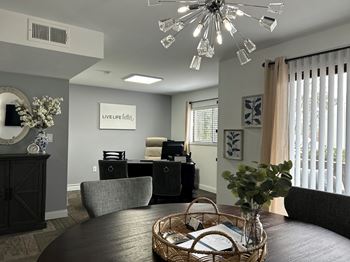 A dining area with a round table and a chandelier above it