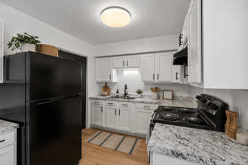 Findlay apartment for rent - A black fridge stands in a kitchen with white cabinets and a marble countertop.
