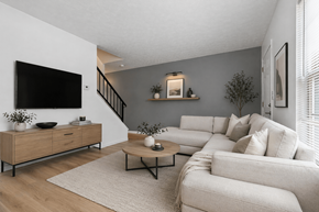 Findlay apartment for rent - A living room with a white couch, a wooden cabinet, and a flat-screen TV mounted on the wall.