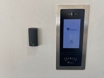 A cell phone hanging on a wall next to a remote control