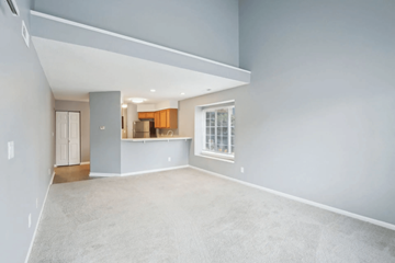 Indianapolis apartment for rent - A spacious living room with a grey carpet and a kitchen area in the background.