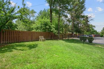 A backyard with a fence and a lawn and a bench