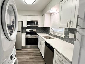 Indianapolis apartment for rent - A modern kitchen with white cabinets and a black backsplash at A62 Apartments, Indianapolis 46220