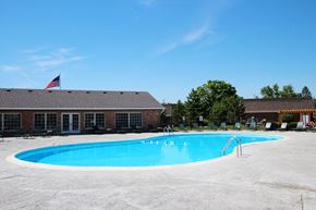 Indianapolis apartment for rent - A swimming pool in front of a building with an American flag at A62 Apartments, Indianapolis 46220
