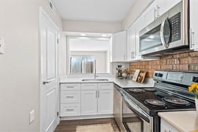 Indianapolis apartment for rent - A kitchen with white cabinets and a brick backsplash at Fountain Parc Apartments, Indianapolis