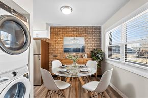 Indianapolis apartment for rent - A modern laundry room with a washing machine and dryer on the left and a dining area with a table and chairs in the middle at Fountain Parc Apartments, Indianapolis, 46220
