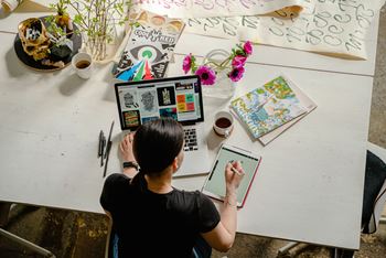 A woman sitting at a desk with a laptop and tablet